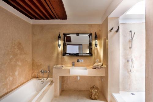 uma casa de banho com um lavatório, uma banheira e um espelho. em Hotel & Spa Dar Bensouda em Fez