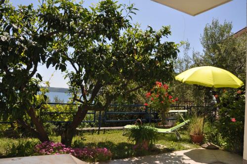 a patio with a yellow umbrella and a bench and flowers at Apartments and Rooms Knez in Portorož