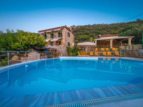 a large blue swimming pool in front of a house at Palataki in Kardamyli