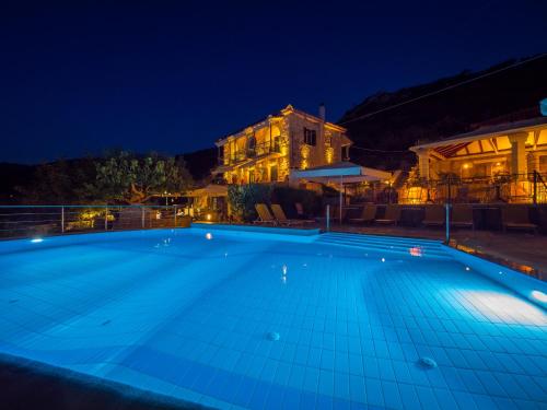 a swimming pool at night with a house in the background at Palataki in Kardamili