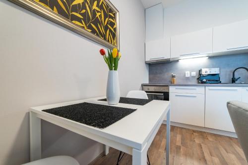 a white table with a vase of flowers on it in a kitchen at MyApartment in the city center in České Budějovice