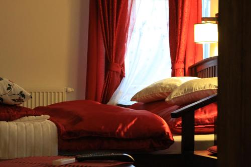a bedroom with two beds with red curtains and a window at Hotel Polak in Zamość