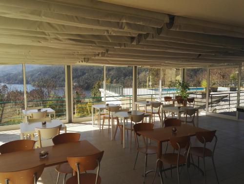 a restaurant with tables and chairs and windows at Hotel Lagoa Azul do Geres in Geres