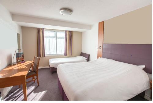 a hotel room with two beds and a desk at Redwings Lodge Solihull in Solihull