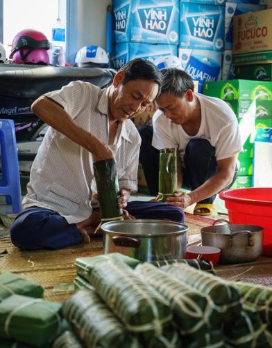 two men sitting on the floor preparing food at Vietnam Phuot Real Home in Kon Tum
