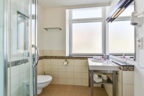 a bathroom with a toilet and a sink and a shower at Hotel PrimaVera parco in Fürth