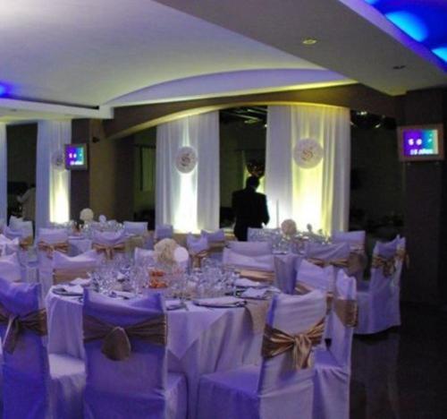 a room with white tables and chairs with a person in the background at Hotel Dos Venados in San Luis