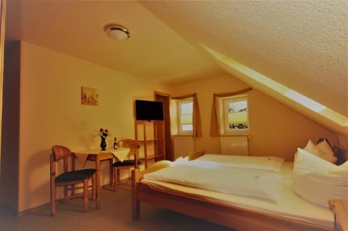 a bedroom with a bed and a table with a chair at Pension Klette in Kurort Oybin