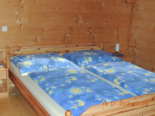 a bed in a wooden room with blue sheets at Egghartguthütte in Tauplitz