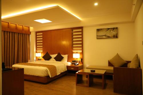 une chambre d'hôtel avec un lit et un canapé dans l'établissement Hotel Karthika Park, à Kazhakuttam