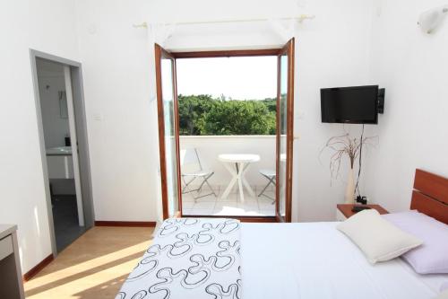 a bedroom with a bed and a balcony with a table at Rooms and Apartment Luana in Rovinj