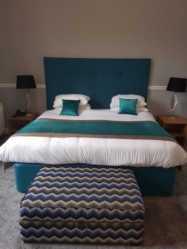 a bedroom with a large bed with a blue headboard at Ardshiel Hotel in Campbeltown