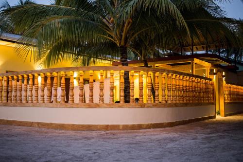 a wooden fence in front of a house with a palm tree at Veli Beach Inn in Mathiveri