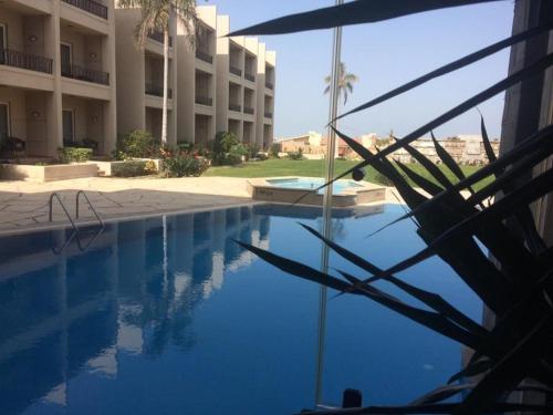 a swimming pool with an umbrella next to a building at Panacea Suites Hotel in Borg El Arab