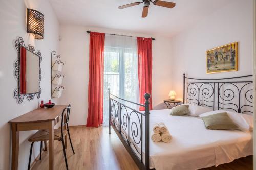 a bedroom with a bed and a desk and a window at Zlatni Bol Apartments in Bol