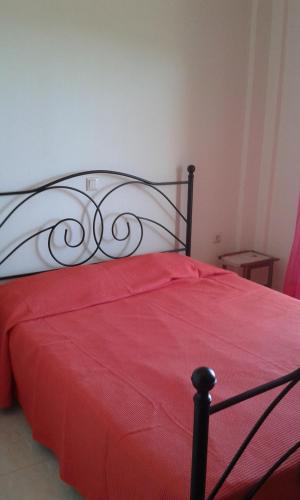 a bedroom with a red bed with a red blanket at House in Front of the Sea in Nea Fokea