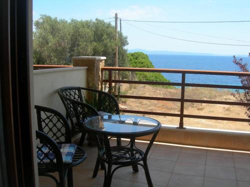 a table and chairs on a balcony with a view of the ocean at House in Front of the Sea in Nea Fokea