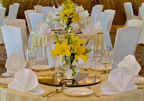 a table with yellow flowers on it with white chairs at Radisson Mumbai Goregaon in Mumbai