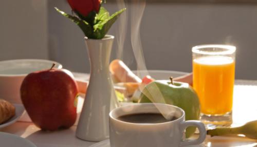 a table with a cup of coffee and fruit and a glass of juice at Nemesis in Fira