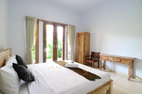 ein Schlafzimmer mit einem großen weißen Bett mit einem Fenster in der Unterkunft The Wina Guest House 2 in Canggu