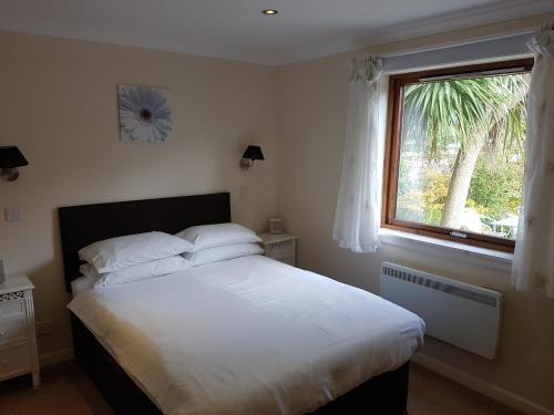 a bedroom with a bed with white sheets and a window at Ardshiel Hotel in Campbeltown