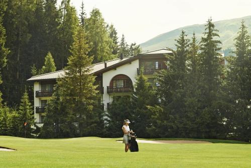 a woman standing in the grass in front of a building at Hotel Waldhuus in Davos