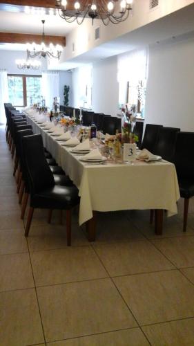 a long table with black chairs and a white table cloth at Karczma Dolina Pstrąga in Machowa