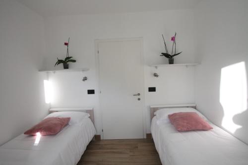 メッツァーナにあるAppartamenti ai Stabli 2の白い壁と植物が特徴の客室で、ベッド2台が備わります。