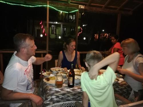 a group of people sitting around a table with food at Mahi Villa in Bentota