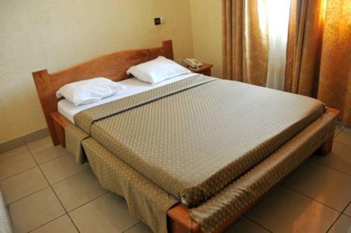 a bed with two pillows on it in a room at First International Inn Downtown in Limbe