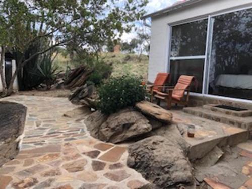 a backyard with a stone patio with two chairs at Halala Africa Lodge - Eagle Rock Lodge in Malabar