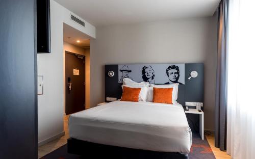 a bedroom with a large white bed with orange pillows at Star inn Lisbon Airport in Lisbon