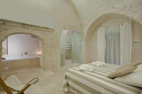 a white bedroom with a large bed and a bath tub at Masserie Maresca in Ostuni