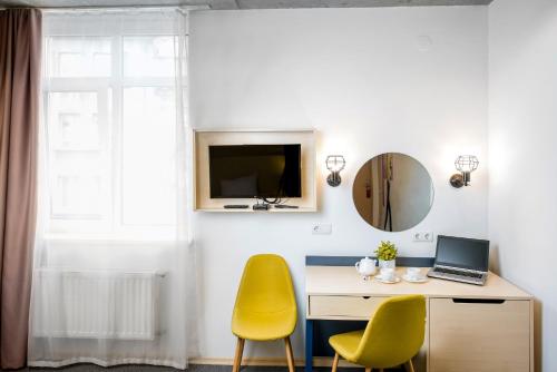 a room with a desk and two yellow chairs at Jam Hotel Hnatyuka in Lviv