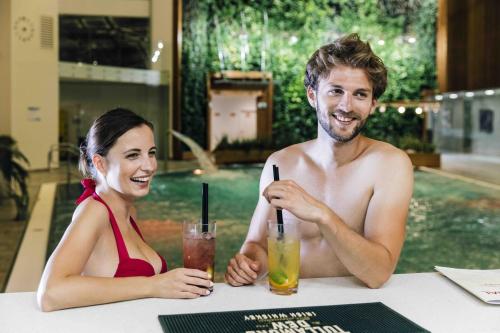 a man and a woman sitting at a table with drinks at Rezort Gothal Chalupy in Donovaly