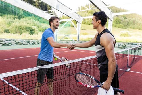 two men shaking hands over the net on a tennis court at Rezort Gothal Chalupy in Donovaly