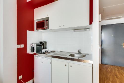 une cuisine blanche avec un évier et un micro-ondes dans l'établissement Champs Elysées George V ID 306, à Paris