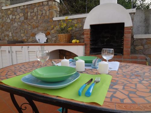 una mesa con platos verdes y copas de vino. en Le Case dei Pescatori - Villa Domitilla, en Ponza