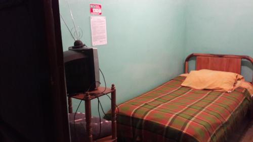 a small bedroom with a bed and a tv at Hostal La Chorrera in Quito