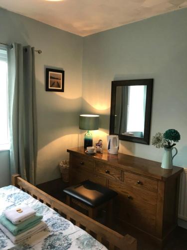 a bedroom with a bed and a dresser with a mirror at The Lobster Pot in Marloes