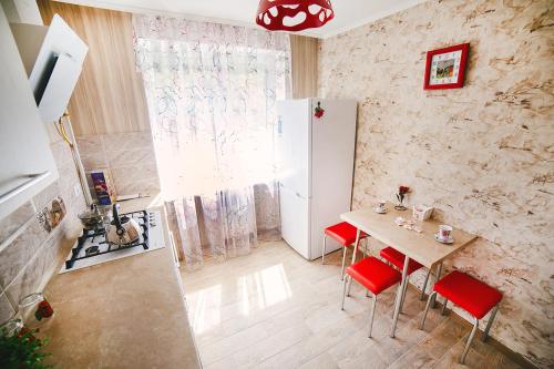 een keuken met een tafel met rode stoelen en een koelkast bij 2-комн ЛЮКС в центре Вишенки in Vinnytsya
