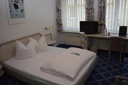 Schlafzimmer mit einem weißen Bett, einem Schreibtisch und einem Computer in der Unterkunft Boardinghaus zu Coburg Residenz in Coburg