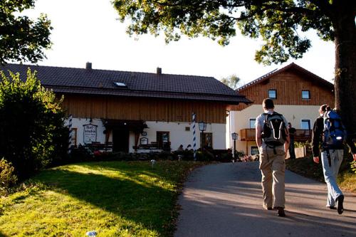 two people walking down a road in front of a house at Hofstub´n in Eschlkam