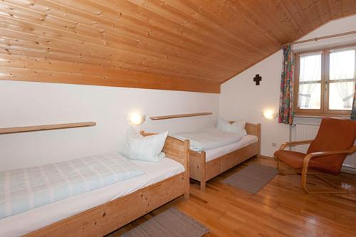 a bedroom with two beds and a chair and a window at Hofstub´n in Eschlkam