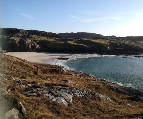 a beach on a hill next to the ocean at Achmelvich View self catering in Lochinver