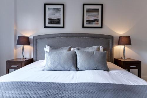 a bedroom with a bed with pillows and two lamps at City Aldgate Apartments in London