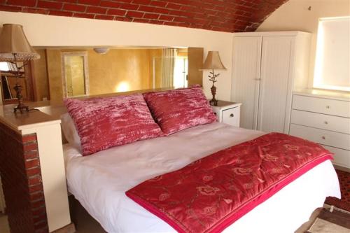 a bedroom with a large bed with red pillows at 43 Artemis in Langebaan