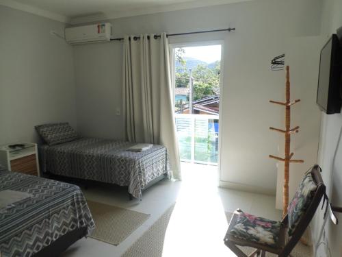 a bedroom with two beds and a sliding glass door at Residencial Camburyá in Camburi
