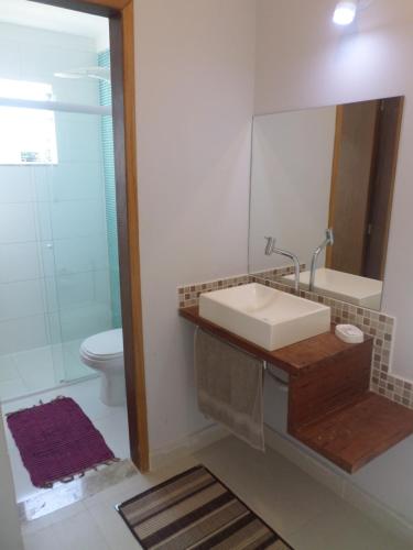 W łazience znajduje się umywalka, lustro i toaleta. w obiekcie Residencial Camburyá w mieście Camburi
