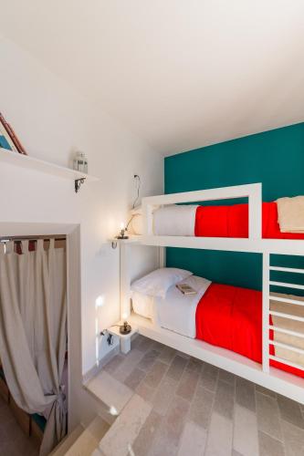 a bedroom with two bunk beds with red and white at Arcuève-Dimora con vista CON TERRAZZE PANORAMICHE in Ostuni